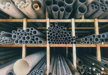 PVC and steel pipes on a shelf in a plumbing supply warehouse